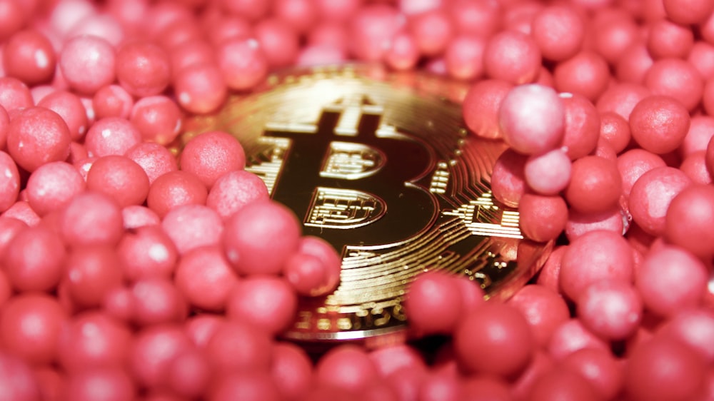 a bitcoin surrounded by pink candy balls