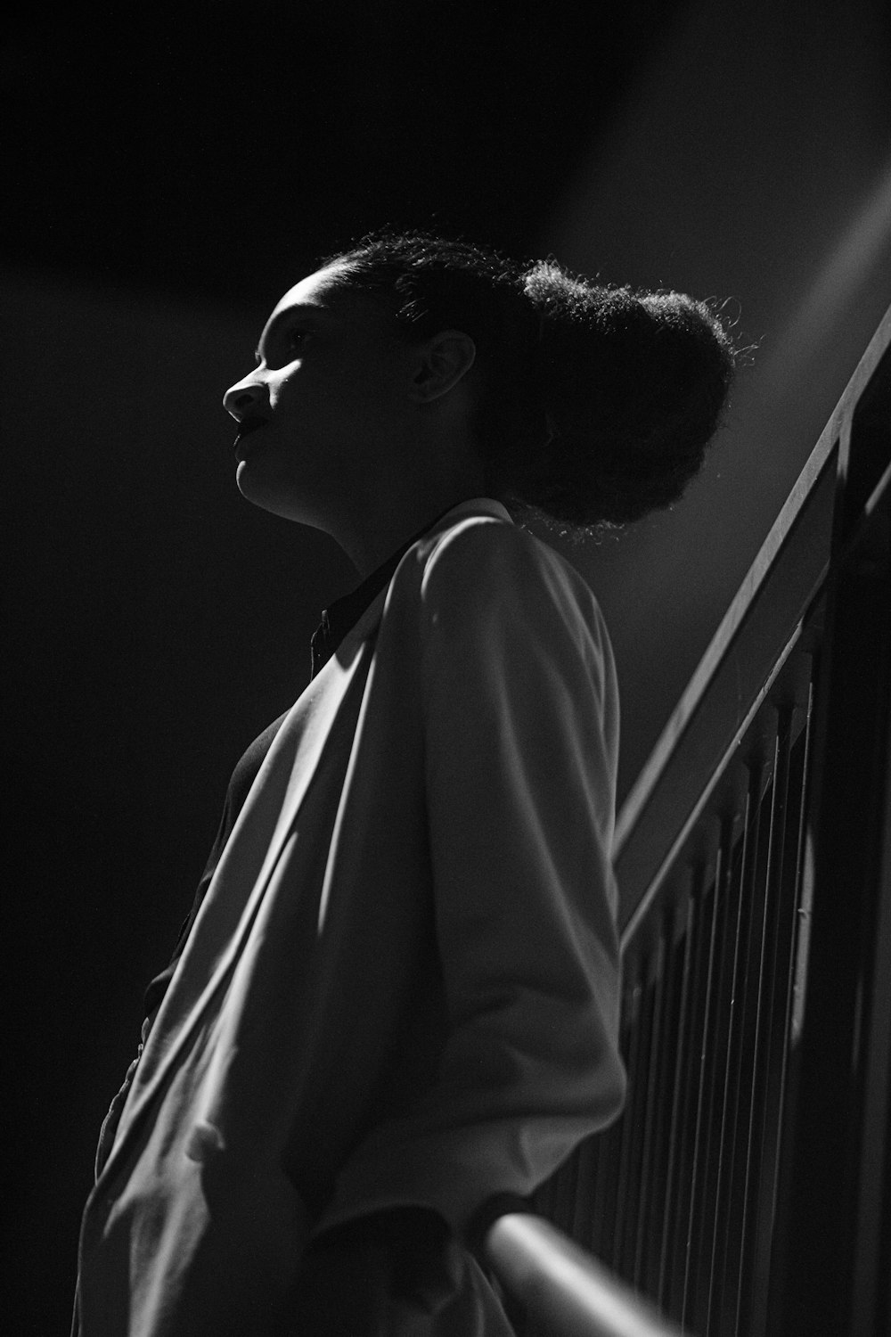 a black and white photo of a woman leaning against a wall