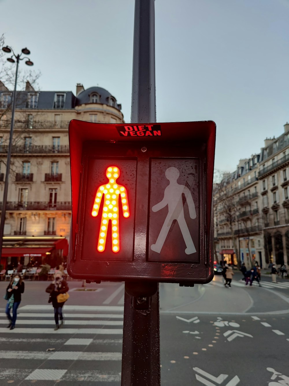 a red pedestrian crossing sign on a city street