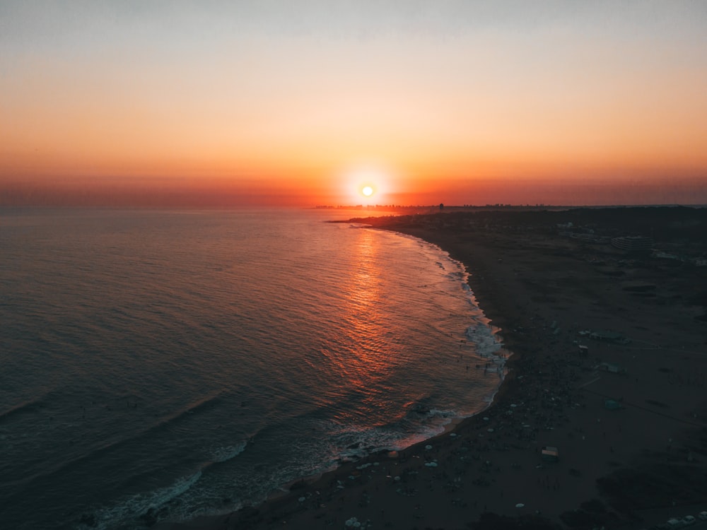 the sun is setting over the ocean on the beach