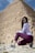 a woman sitting on the ground in front of a pyramid
