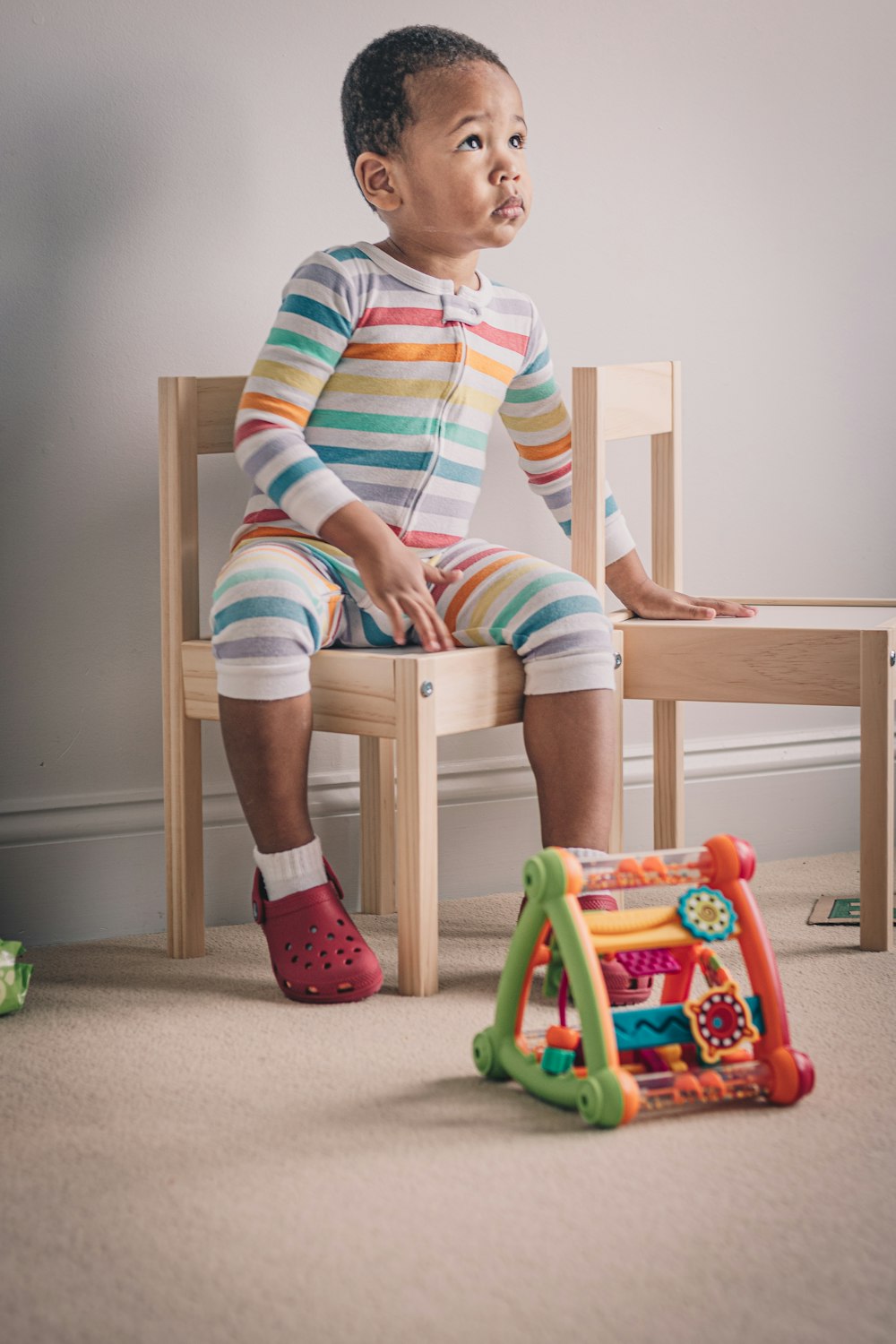 a little boy sitting on a chair next to a toy