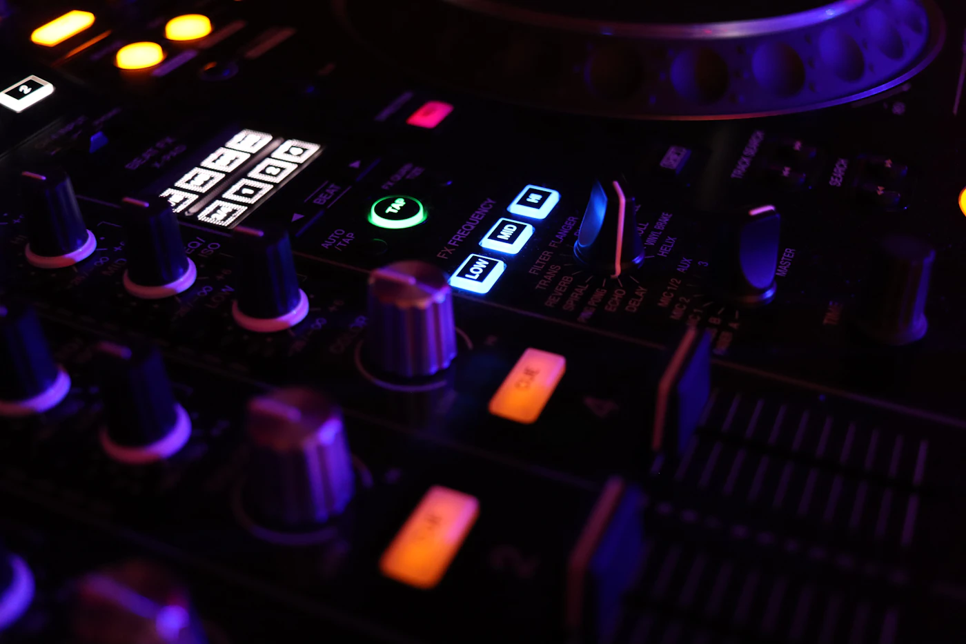 DJ mixer controls and illuminated EQ buttons in a dark club setting