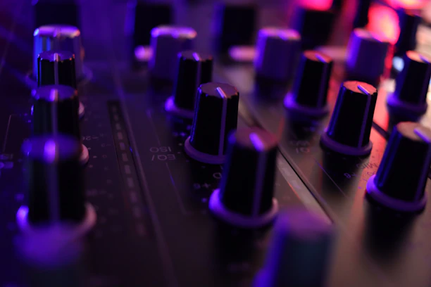 Close-up of a soundboard with glowing neon controls in a professional music studio