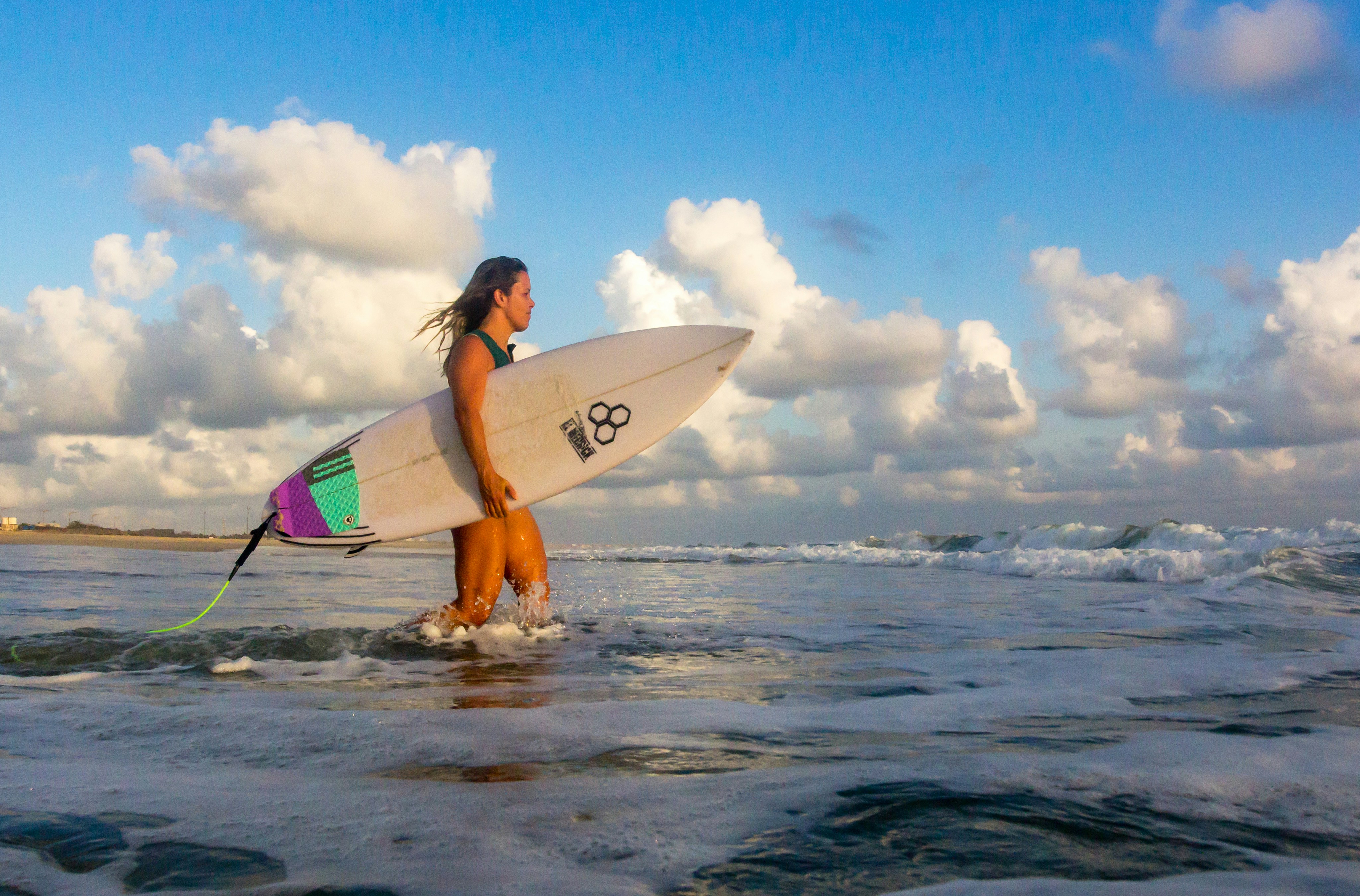 a woman holding a surfboard walking into the ocean