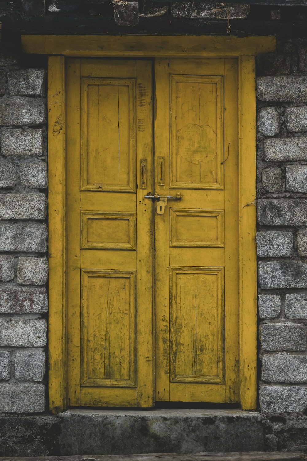 a yellow door with a brick wall behind it