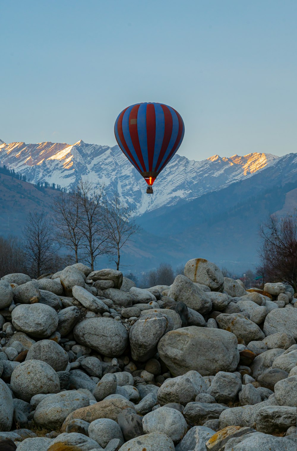 a hot air balloon flying over a rocky hillside