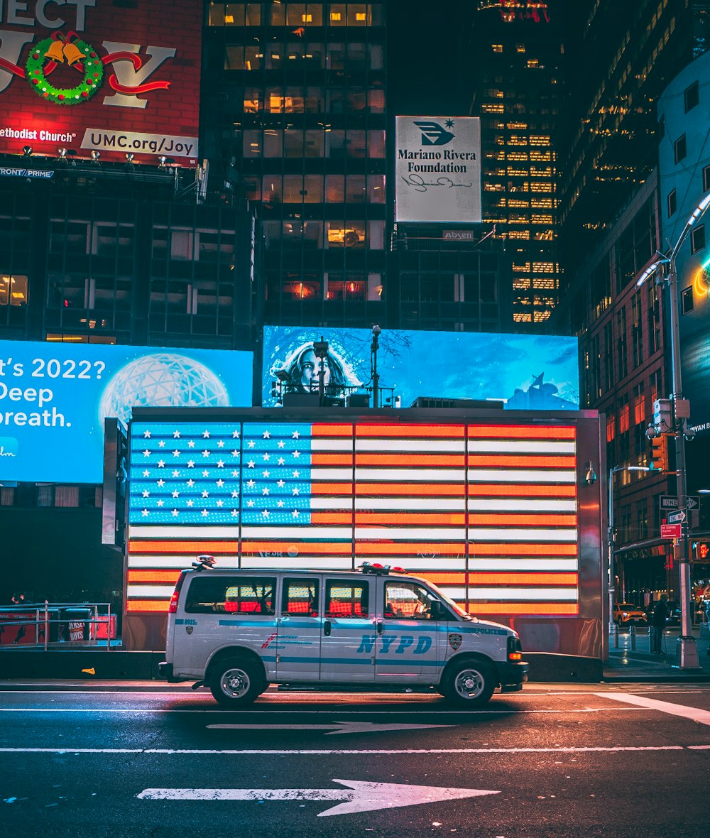 a van driving down a street next to tall buildings