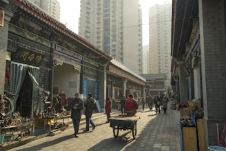 a group of people walking down a street next to tall buildings