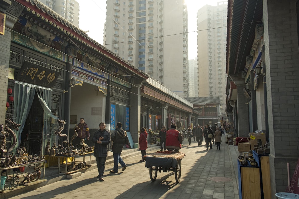 a group of people walking down a street next to tall buildings