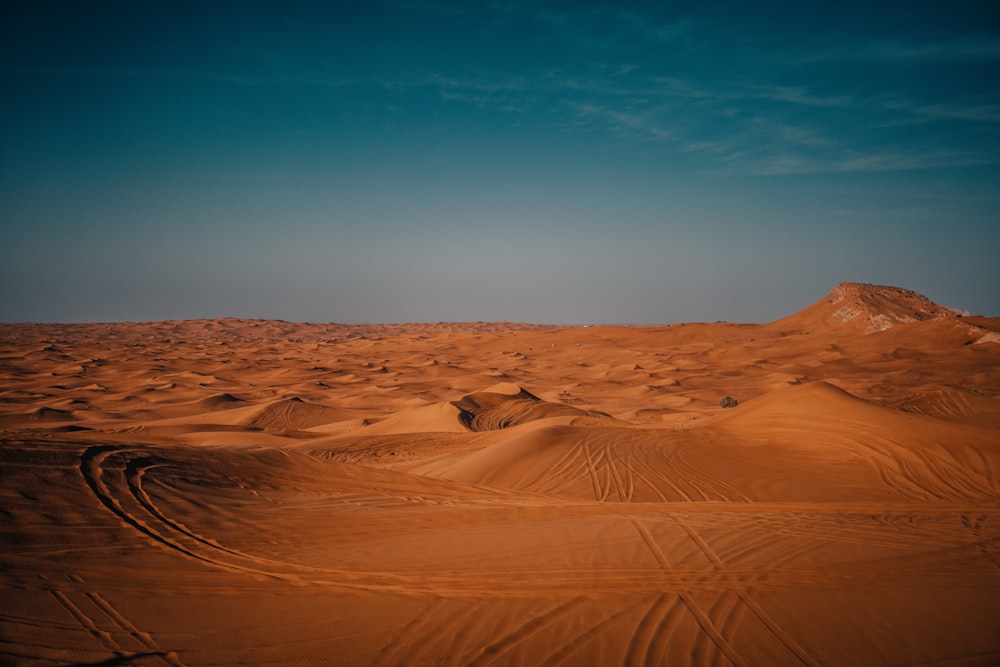 a desert landscape with sand dunes and a mountain in the distance