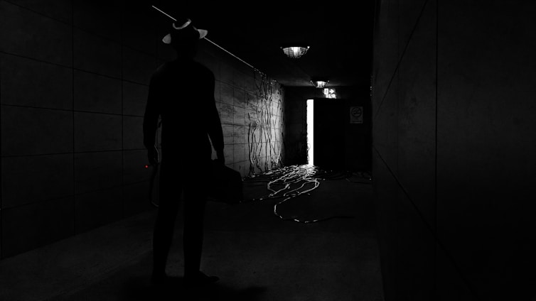 A shadowy figure handing over a briefcase in a dimly lit urban alley.