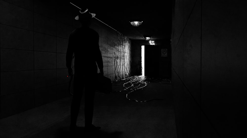 a man standing in a dark hallway with a cane in his hand