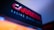 A close-up of a sign featuring the word 'Carrera' in bold, red letters, accompanied by the phrase 'Racing since 1963' in smaller, white text below it. The background is dark, creating a contrast with the illuminated text, and there is a gradient of blue tones visible above the sign.