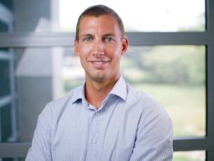 a man in a blue shirt standing in front of a window