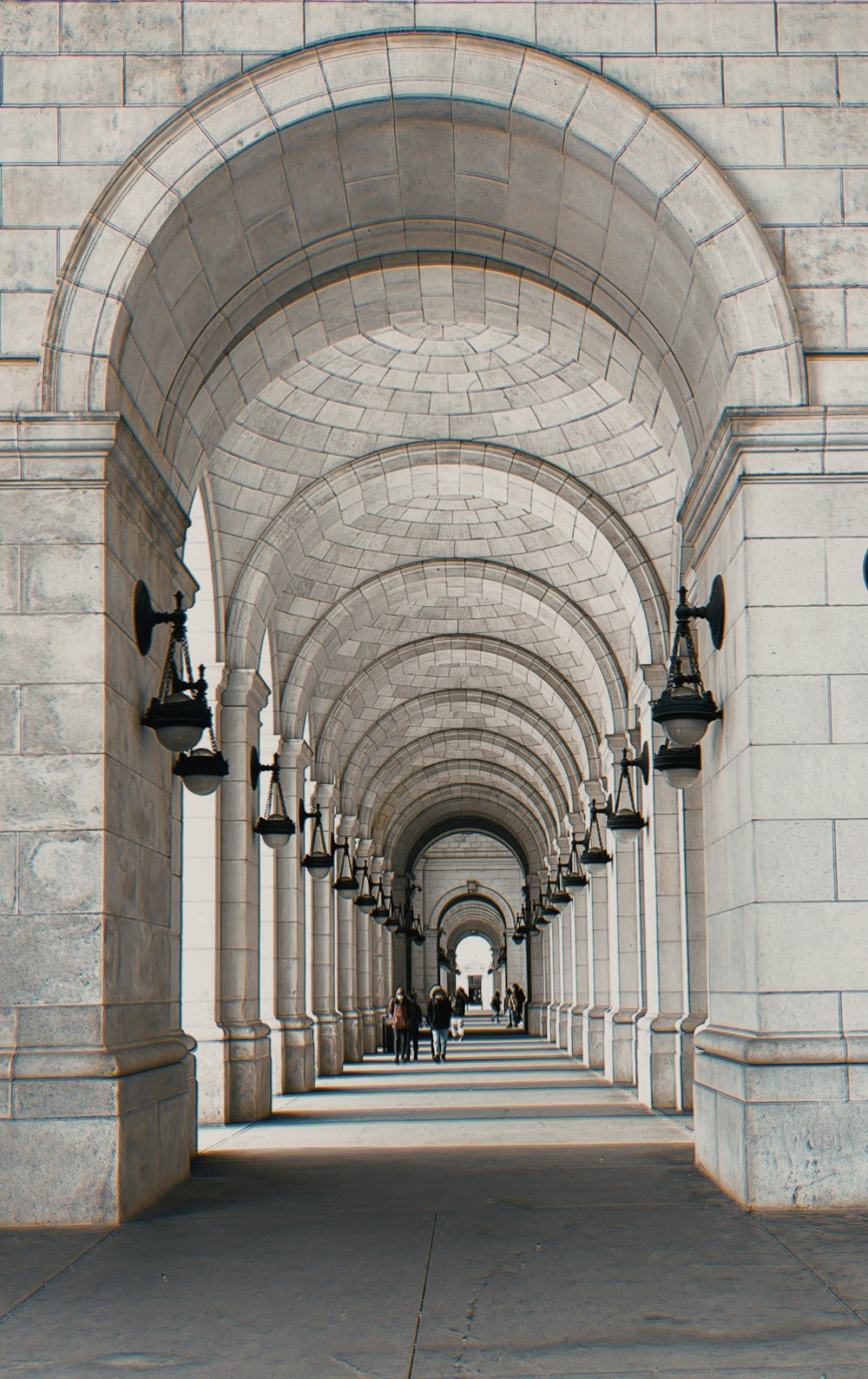 a walkway lined with stone arches and street lamps