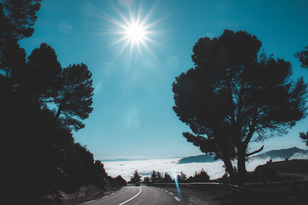 the sun is shining above the clouds and trees