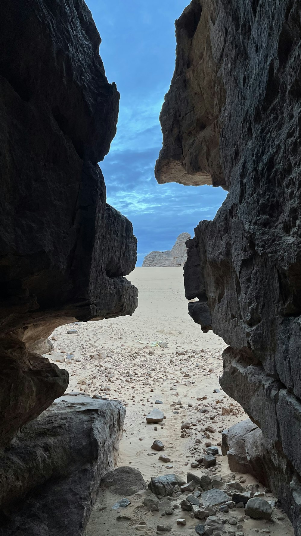 a view of a sandy beach through two rocks