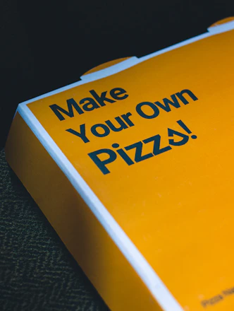 a close up of a pizza box with the words make your own pizza