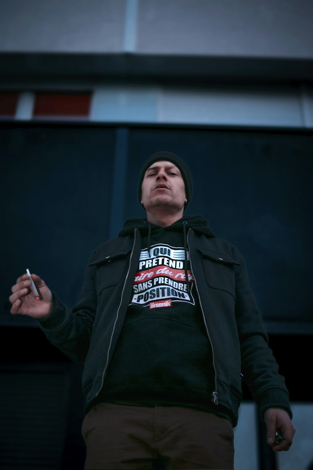 a man standing in front of a building holding a cigarette