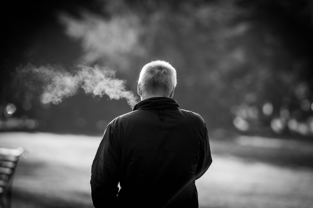 a man standing next to a park bench with a lot of smoke coming out of