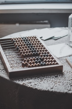 a close up of a table with an abacus, paper and glass of water