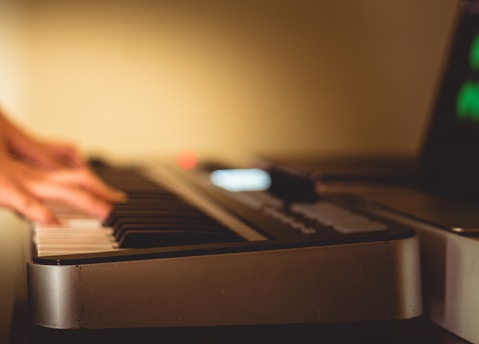 A close-up of a musician's hands blending traditional instruments with futuristic AI interfaces in a dimly lit studio.