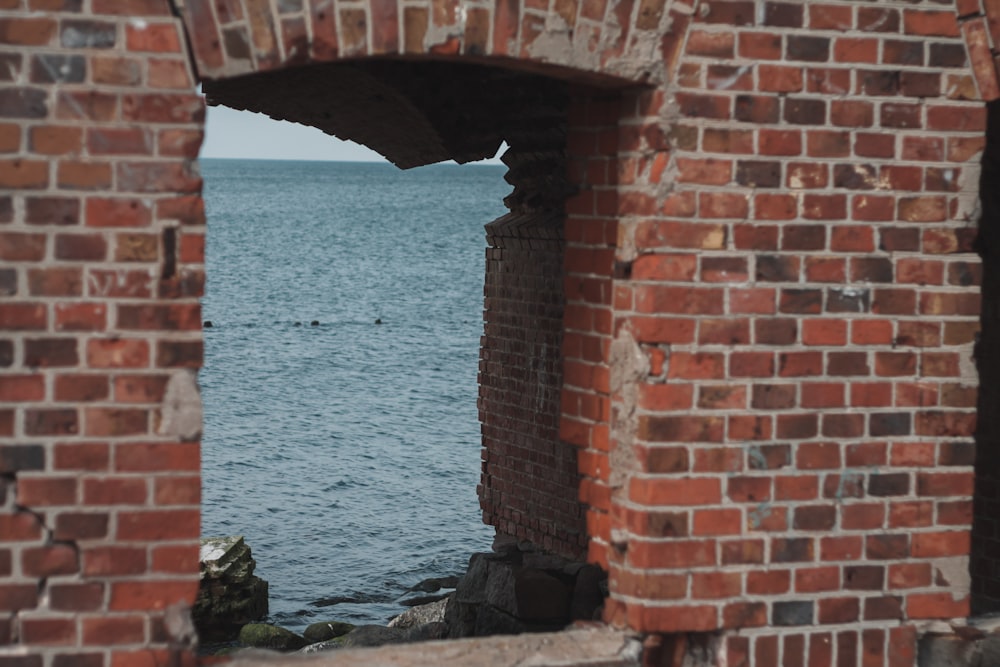 a view of a body of water through a brick wall
