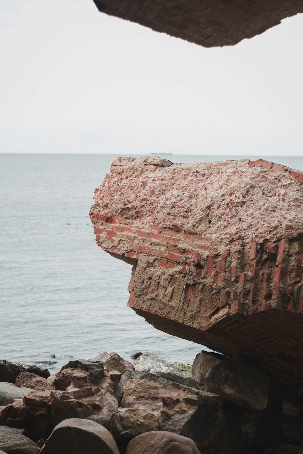 a large rock sitting on top of a beach next to the ocean