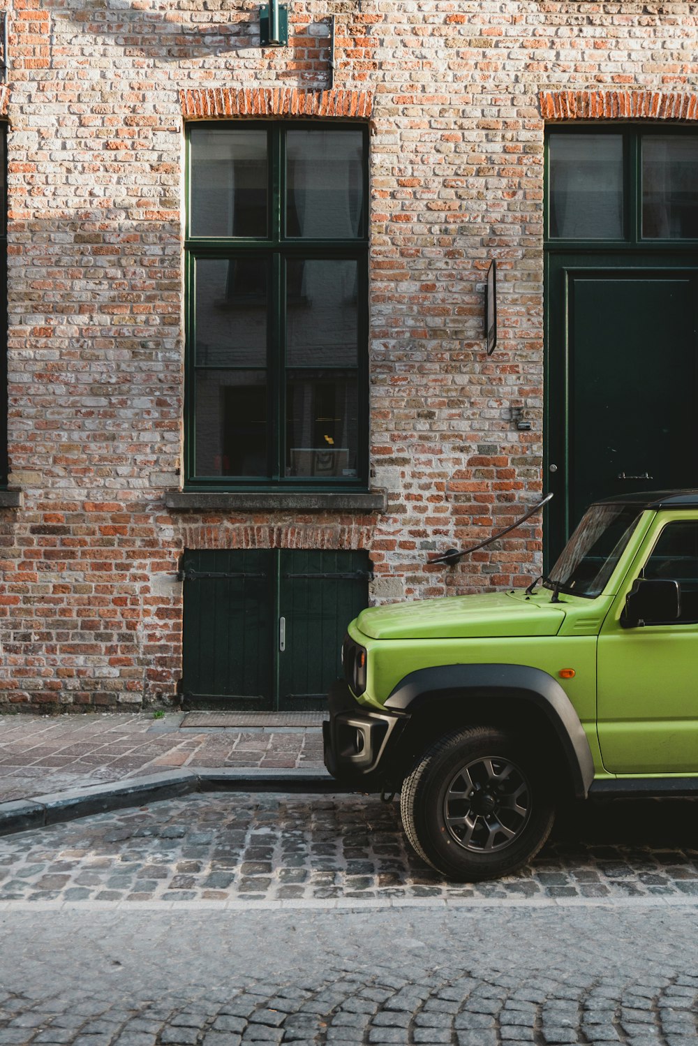 a green truck parked in front of a brick building