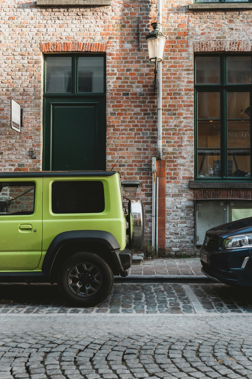 a bright green jeep parked in front of a brick building