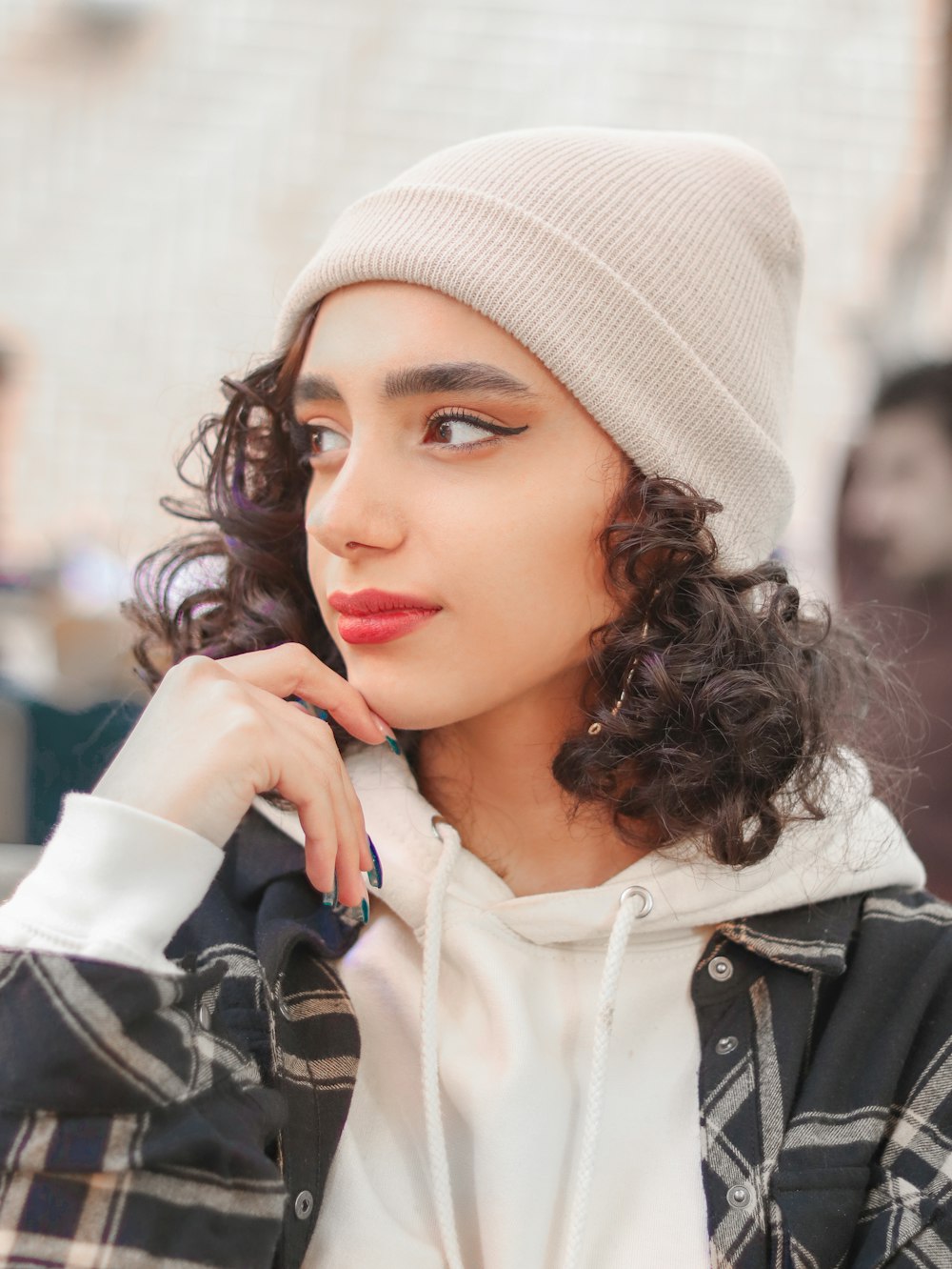 a woman with curly hair wearing a beanie