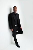 a man in a suit leaning against a wall