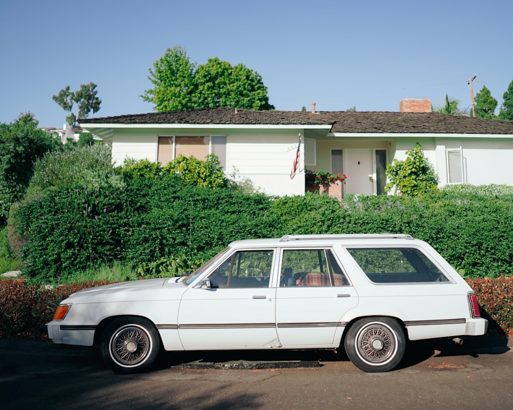 a white car parked in front of a house