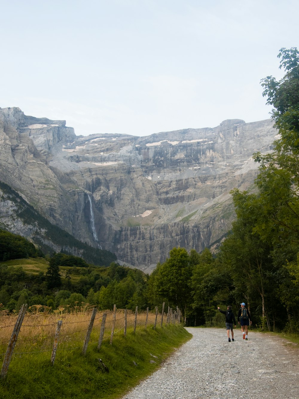 a couple of people walking down a dirt road