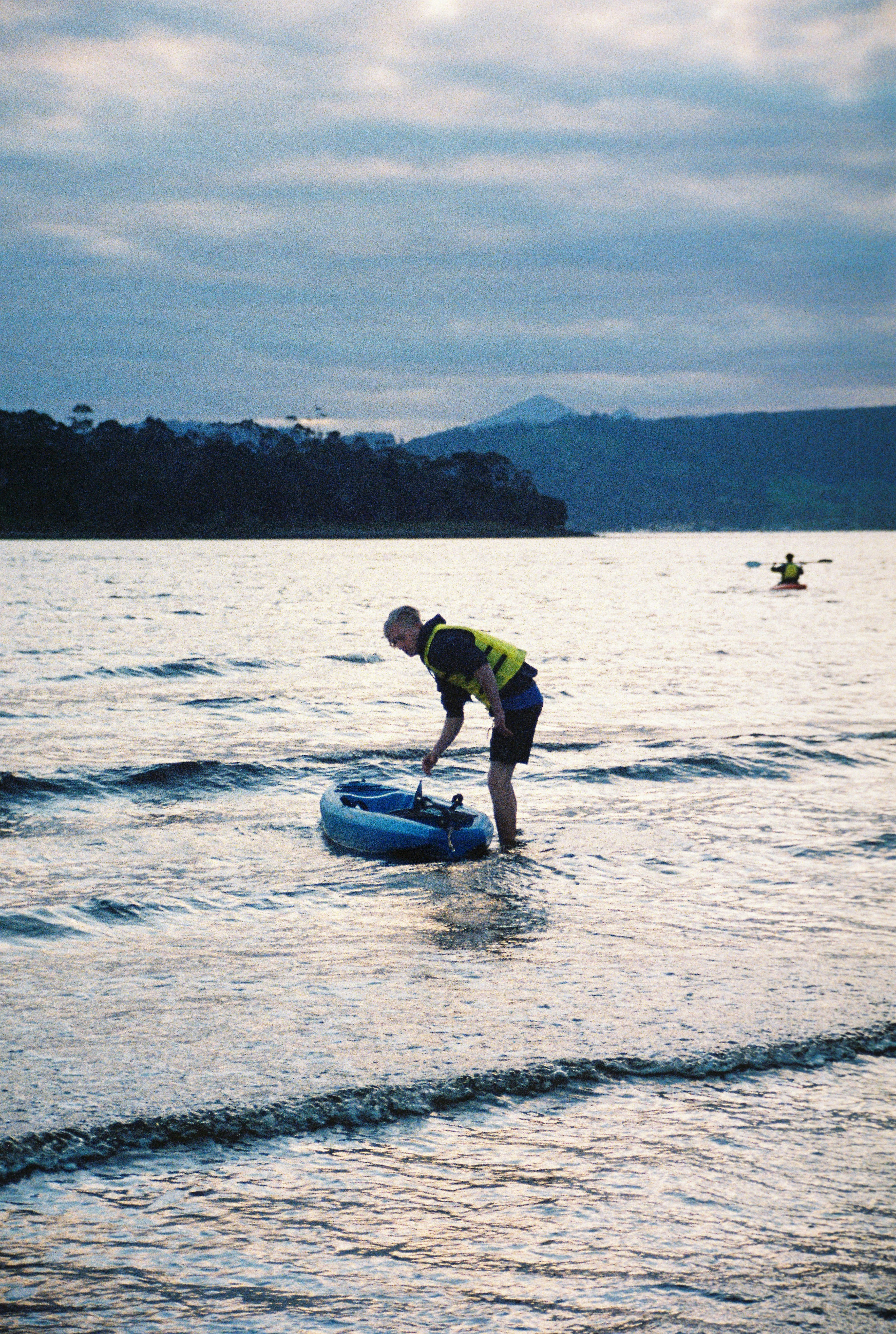 a man standing in the water next to an inflatable boat