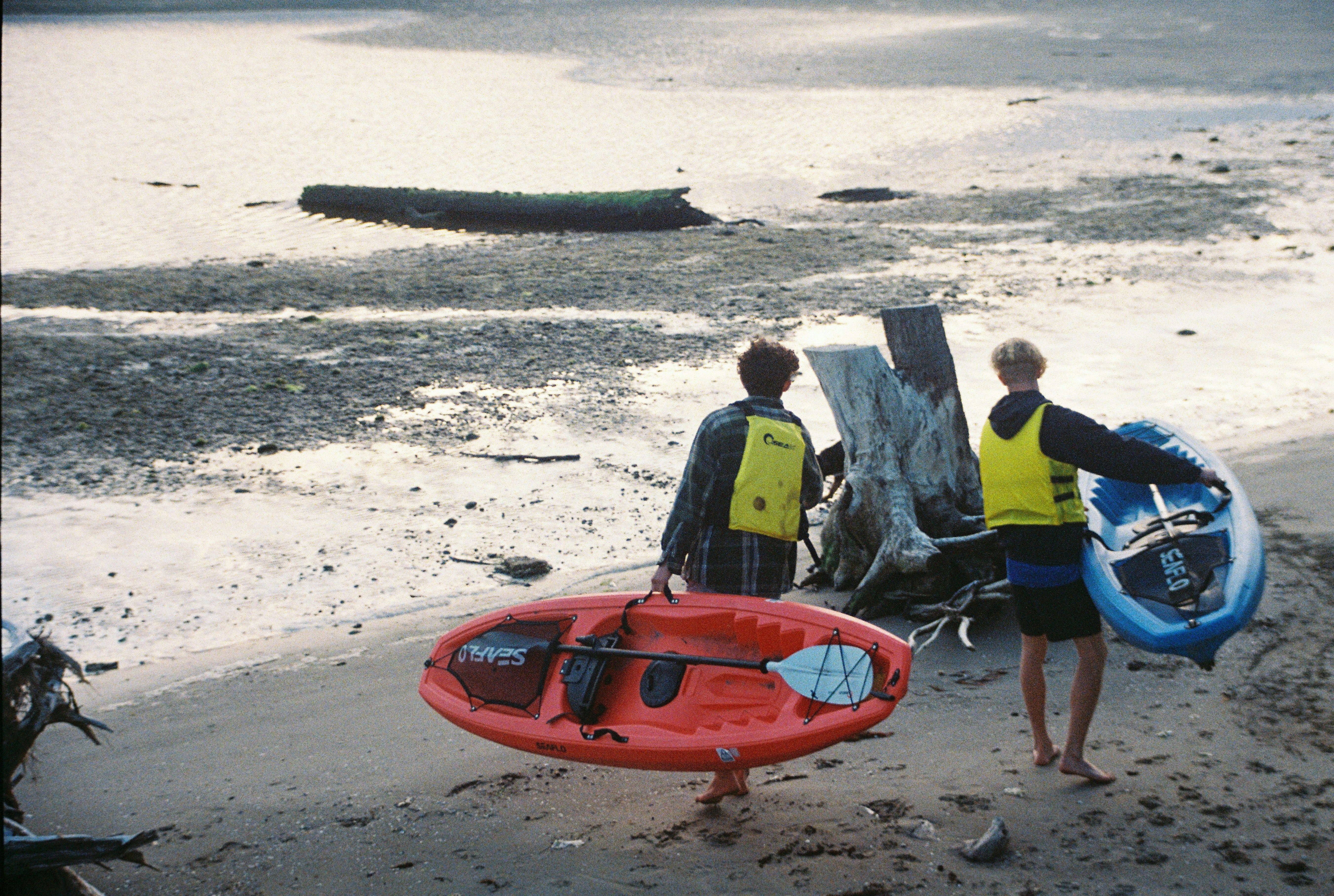 a couple of men standing on top of a beach next to a body of water