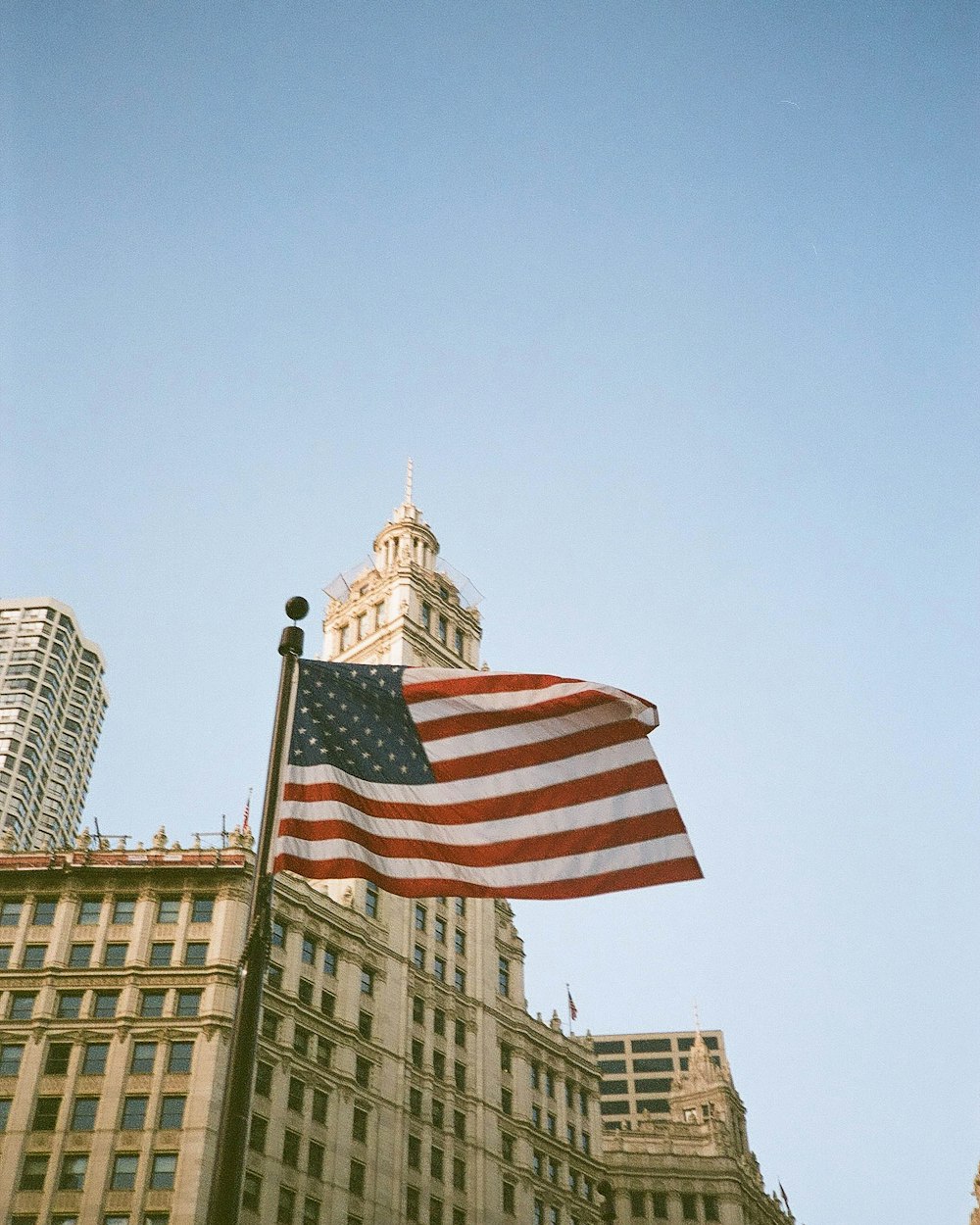 an american flag flying in front of a tall building