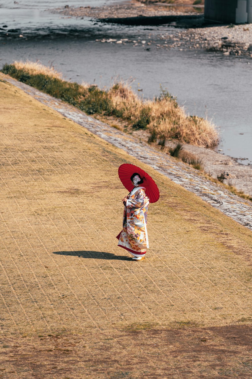 Une femme avec un parapluie rouge marchant sur un trottoir