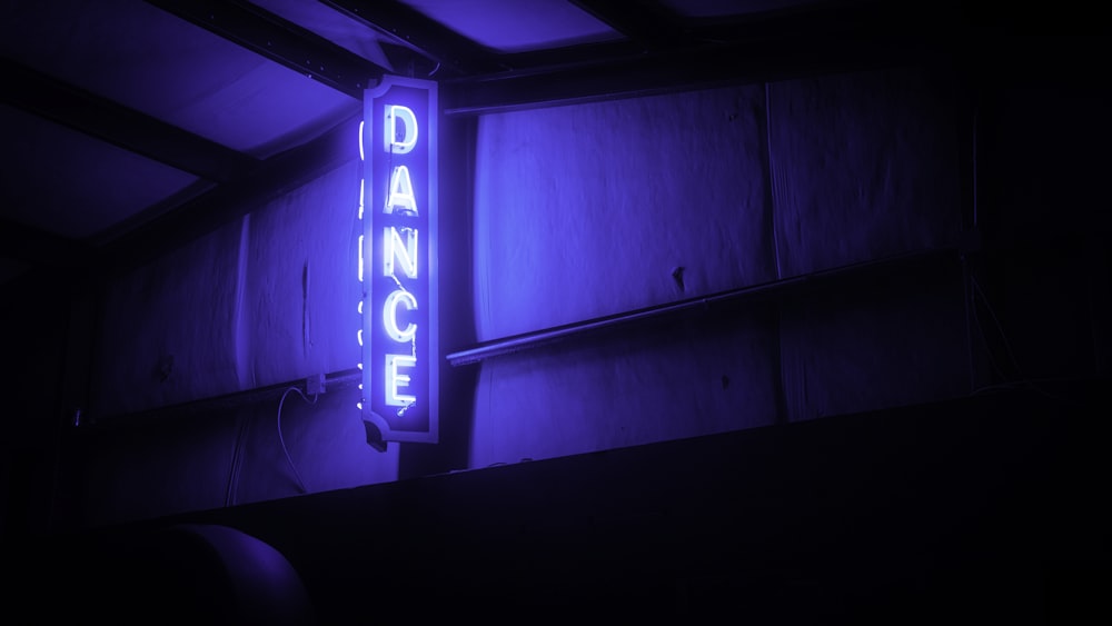 a neon dance sign lit up in the dark