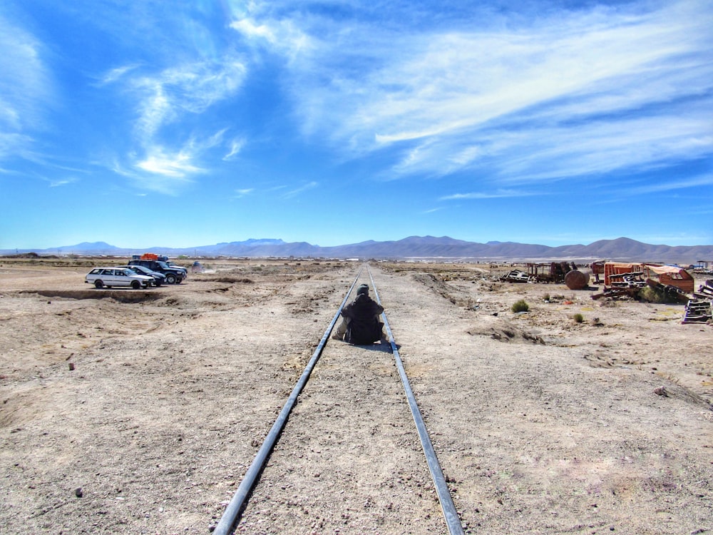 a person sitting on a train track in the middle of nowhere