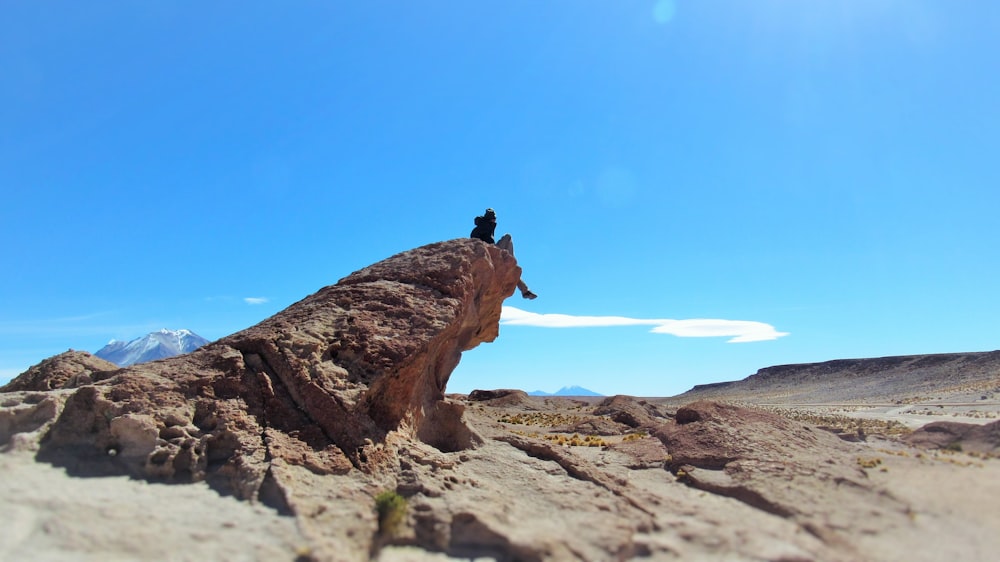 a person sitting on top of a large rock