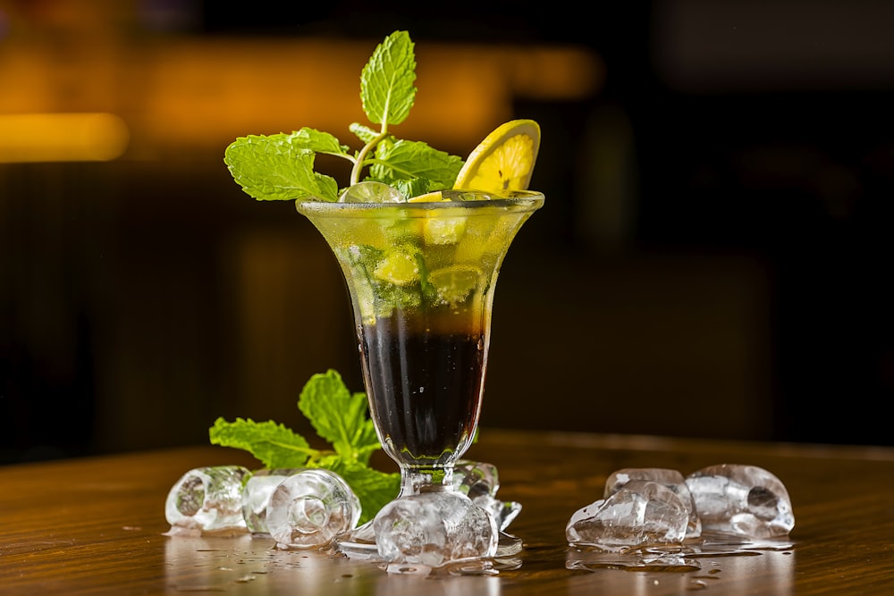 a tall glass filled with ice and a lemon slice