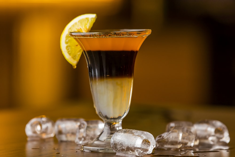 a glass filled with liquid and ice on top of a table