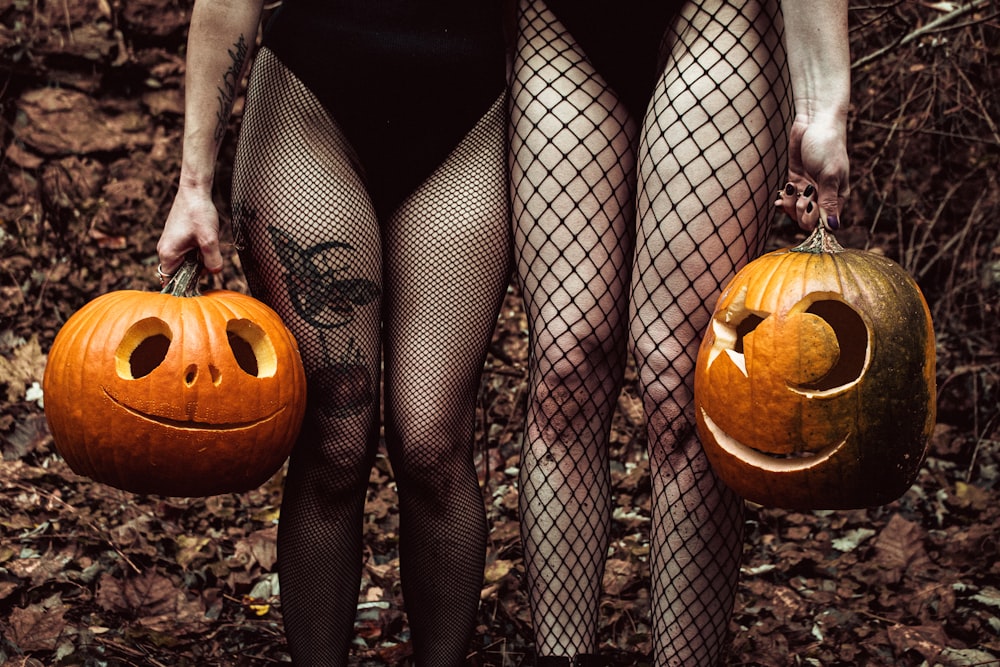 a woman in fishnet stockings holding two pumpkins