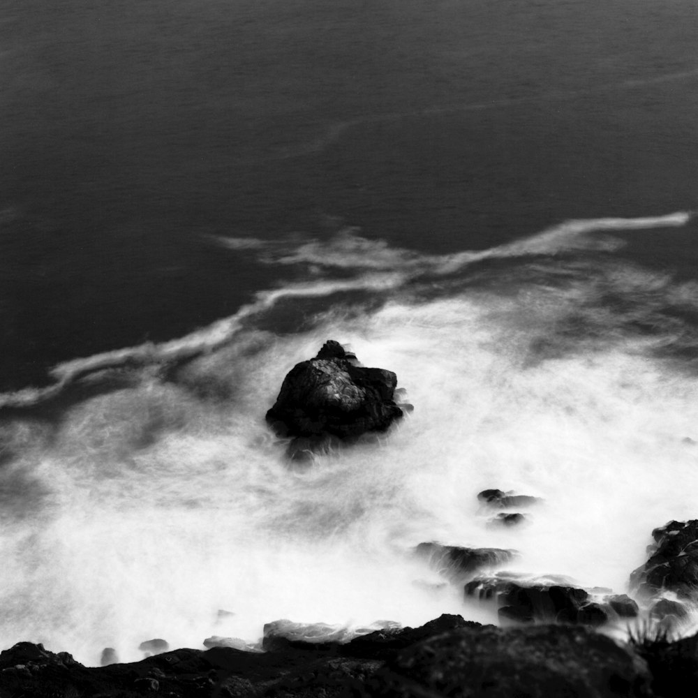 Una foto en blanco y negro de una roca en el océano