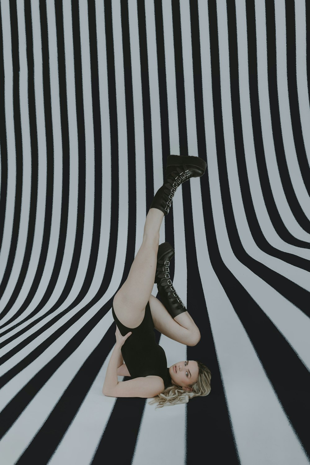a woman laying on the ground in front of a black and white striped wall