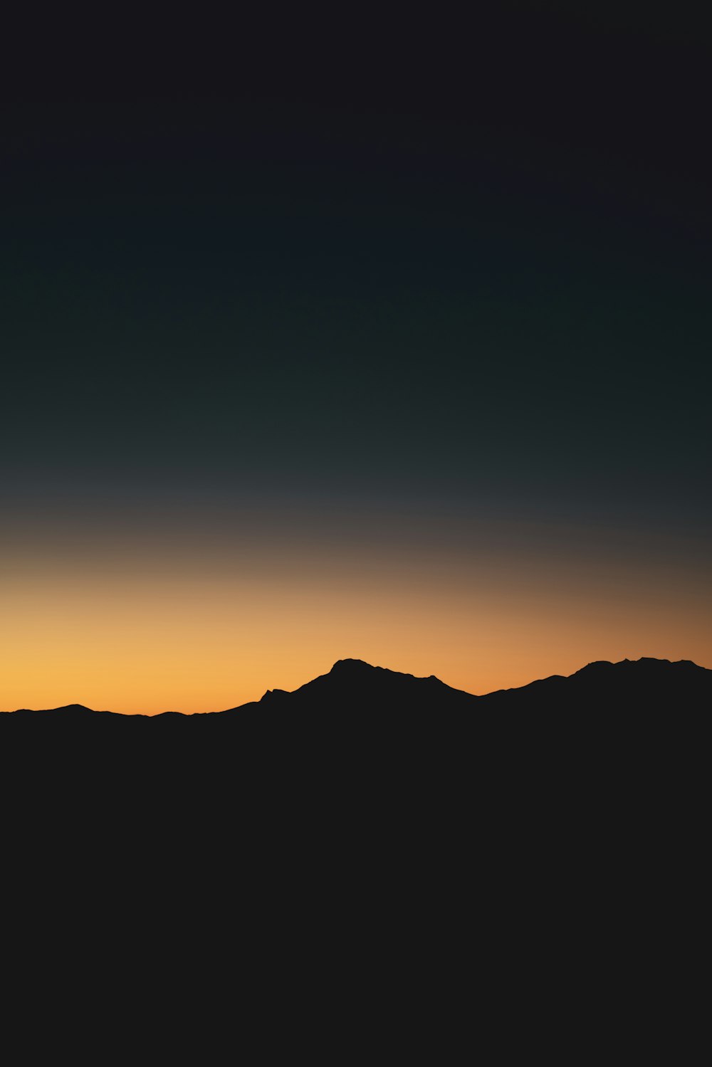 a plane flying over a mountain range at sunset