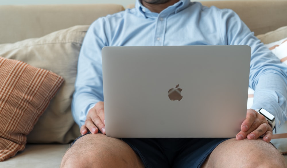 a man sitting on a couch holding a laptop