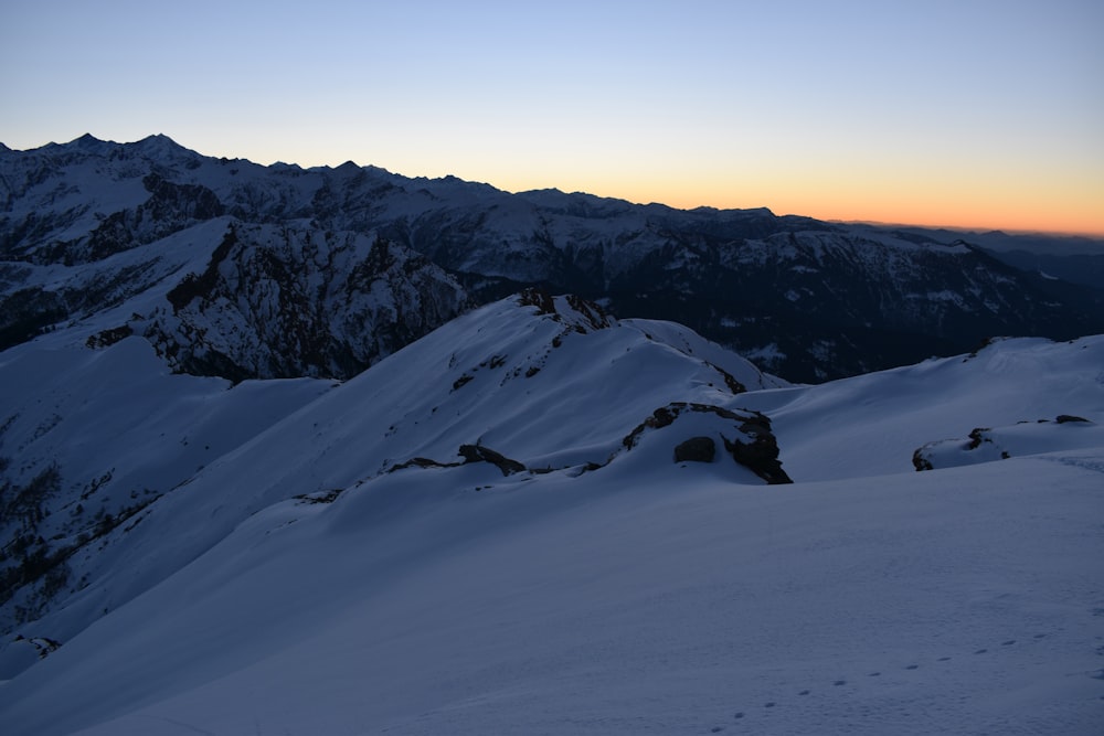 a mountain covered in snow with a sunset in the background